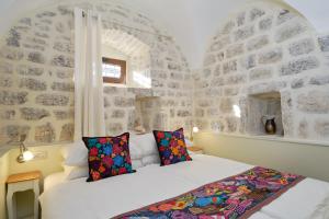 a bedroom with a white bed in a stone wall at Apartments Zebra in Tivat