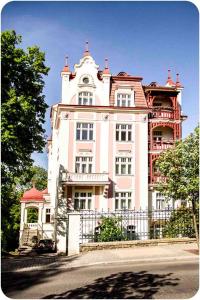 duży różowy budynek z zegarem w obiekcie Apartmán Vila Bayer w Karlowych Warach