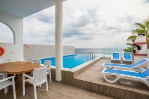 a villa with a swimming pool and a table and chairs at The Sea-Bank Villa Apartments in Marsaskala