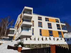 a building with snow in front of it at Apartamenty Willowa in Szczyrk