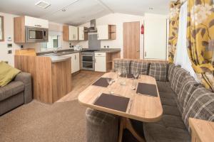 a kitchen and living room with a table and a couch at Trelawne Manor Holiday Park in Looe