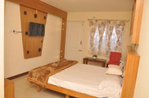 a bedroom with a bed and a tv on the wall at Drizzle Drop Inn in Ooty