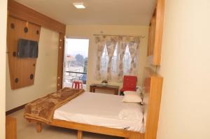 a small bedroom with a bed and a window at Drizzle Drop Inn in Ooty