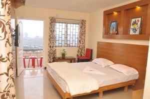 a bedroom with a bed and a balcony at Drizzle Drop Inn in Ooty