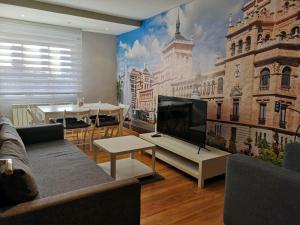 a living room with a tv and a mural of a building at Apartamento GO Felipe II Center in Valladolid