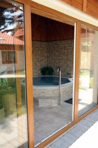 a sliding glass door with a tub in a house at Arany Szőlő Wellness Apartmanház in Hévíz