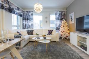 a living room with a white couch and a christmas tree at Tuomas´ luxurious suites, Livo in Rovaniemi