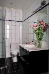 a bathroom with a toilet and a sink with a vase of flowers at Frogner House - Skovveien in Oslo