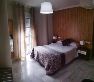 sypialnia z łóżkiem i dużym oknem w obiekcie Hostal Tilos w Maladze