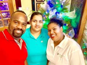 two men and a woman standing in front of a christmas tree at Seaview Inn in Basseterre
