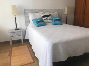 une chambre avec un lit blanc avec des oreillers bleus dans l'établissement FLATS ON THE BEACH BALCONADA I, à La Paloma