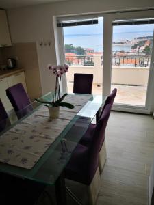 una mesa de comedor con sillas moradas y un jarrón con flores en Apartment Aria, en Rab