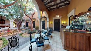 a restaurant with a bar and tables and chairs at Hotel Boutique La Mision De Fray Diego in M&eacute;rida