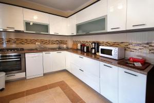 uma cozinha com armários brancos e um micro-ondas em Vila Moldavia Class em Slănic-Moldova