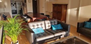 a living room with a leather couch and a table at Appartement in residentie Silverbeach met binnenzwembad in De Haan