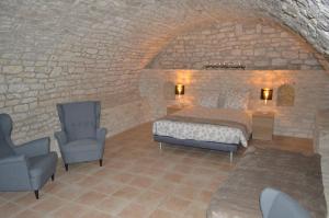 a bedroom with a bed and a chair in a stone wall at Gîte Manoir in Bouloc +15 photos