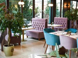 ein Restaurant mit Tischen, Stühlen und Pflanzen in der Unterkunft Hotel SunGarden Salin in Turda