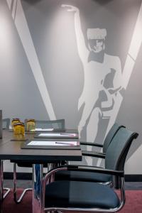 a table with chairs and a picture of a man on a wall at Mercure München City Center in Munich
