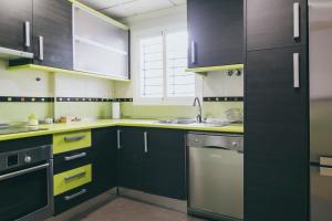 a kitchen with black and yellow cabinets and a dishwasher at Apartamento Torremolinos Centro in Torremolinos