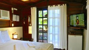 a bedroom with a bed and a tv and a window at Complexo de Pousadas Caraguatá in Ilha do Mel