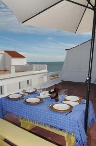 a table with plates and glasses and an umbrella at Rossio in Albufeira