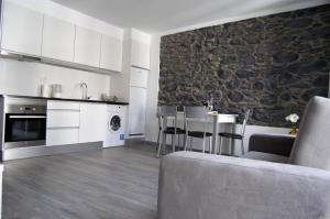 a kitchen and living room with a stone wall at Apartamentos Funchal by Petit Hotels in Funchal