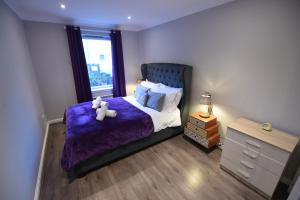a bedroom with a purple bed with a teddy bear on it at Royal Mile Apartment in Edinburgh