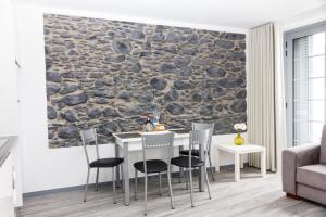 Apartamentos Funchal by Petit Hotels في فونشال: جدار حجري في غرفة معيشة مع طاولة وكراسي