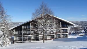 um grande edifício na neve com uma árvore em Apartment Almberg em Mitterfirmiansreut