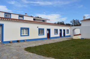 a white building with blue doors and a yard at Herdade Ribeira de Borba in Vila Viçosa