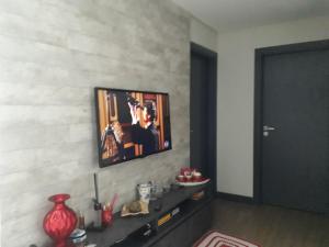 a living room with a television on a wall at Hospedagem Domiciliar Central in Jaraguá do Sul