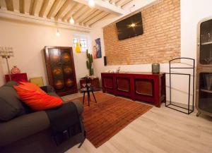 een woonkamer met een bank en een tv aan een bakstenen muur bij House of Joy in Venetië
