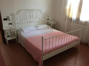 ein Schlafzimmer mit einem weißen Bett mit einer rosa Decke in der Unterkunft Villetta le Rose in Tavullia