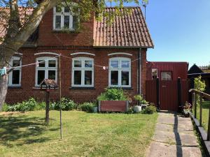 una casa de ladrillo con una valla en el patio en Det lille røde hus, en Nyord