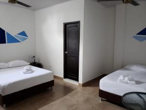 1 dormitorio con 2 camas y puerta negra en Hotel Puerto Azul, en Puerto Berrío