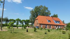 a large house with an orange roof on a field at Ferienwohnung Thien in GroÃŸ Niendorf