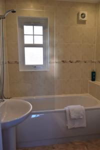 a bathroom with a tub and a sink and a window at Cladach in Garlieston