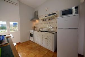 eine Küche mit weißen Schränken und einem weißen Kühlschrank in der Unterkunft Bungalows del Lago - Astbury Formentera in La Savina