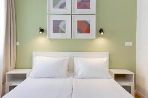 een slaapkamer met een wit bed met 2 kussens bij Dinostratus House in Athene