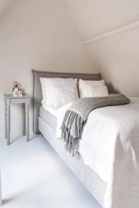 a white bedroom with a bed and a side table at Maison de l'Epée in Emmeloord