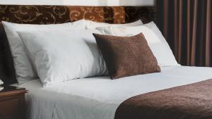 1 cama con almohadas blancas y almohada marrón en Faraona Grand Hotel en Lima