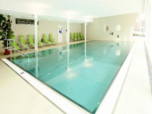 a swimming pool with blue water in a building at Hotel Royal X in Seeboden