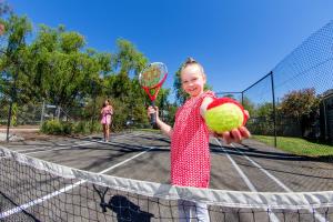 a little girl holding two tennis balls and a racket at NRMA Ballarat Holiday Park in Ballarat