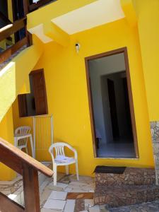 een geel huis met twee stoelen en een spiegel bij Casa da Val in Morro de São Paulo