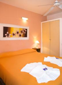 Un dormitorio con una cama naranja con toallas. en Hotel Los Aromos en Mina Clavero