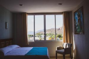 1 dormitorio con cama, ventana y silla en HOTEL DE LA PEÑA INN, en Santo Domingo Tehuantepec