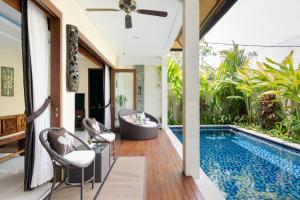 a patio with a swimming pool and chairs next to a house at Kubu Gajah Villas in Sanur
