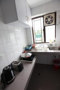 eine kleine weiße Küche mit einem Waschbecken und einem Fenster in der Unterkunft Lantau Lodge in Hongkong