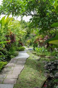 a stone path in a garden with trees and plants at Villa Chempaka in Ubud