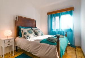 um quarto com uma cama com cortinas azuis e uma janela em Lisboa Manaia Home em Lisboa